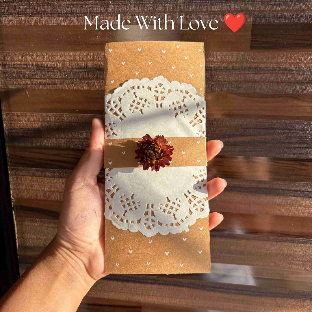 handmade kraft paper envelope or card with a white paper doily and a small dried flower.