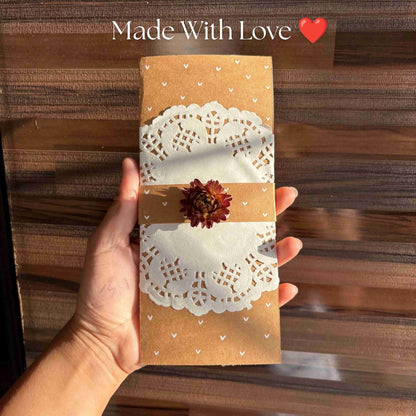 handmade kraft paper envelope or card with a white paper doily and a small dried flower.
